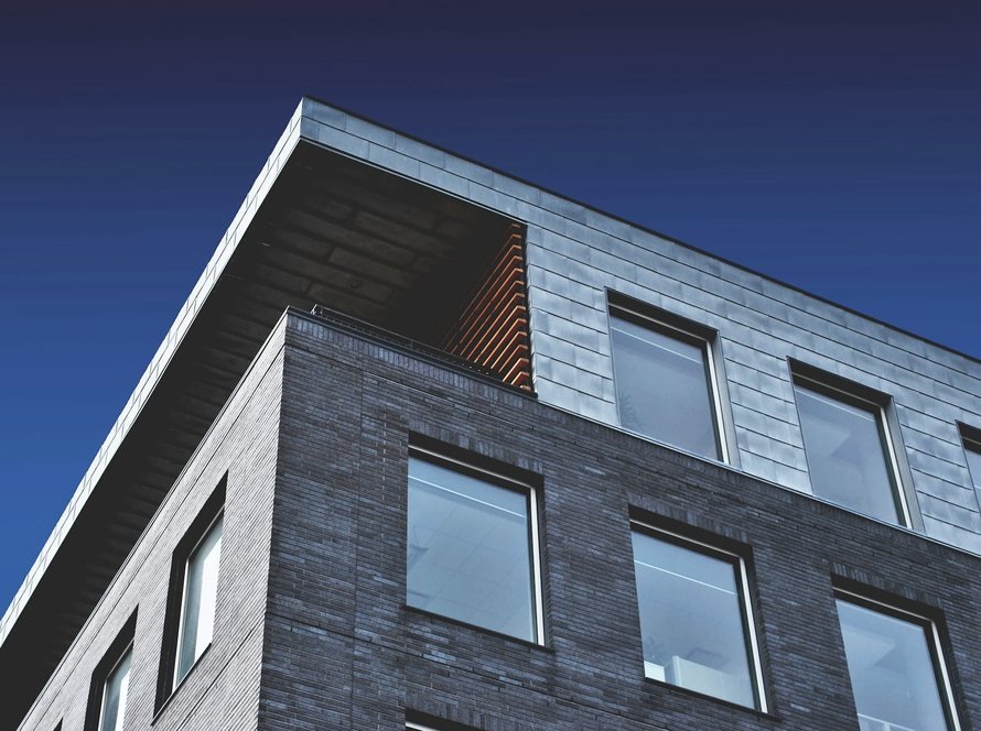 Modern brick and metal-clad building corner against a deep blue sky