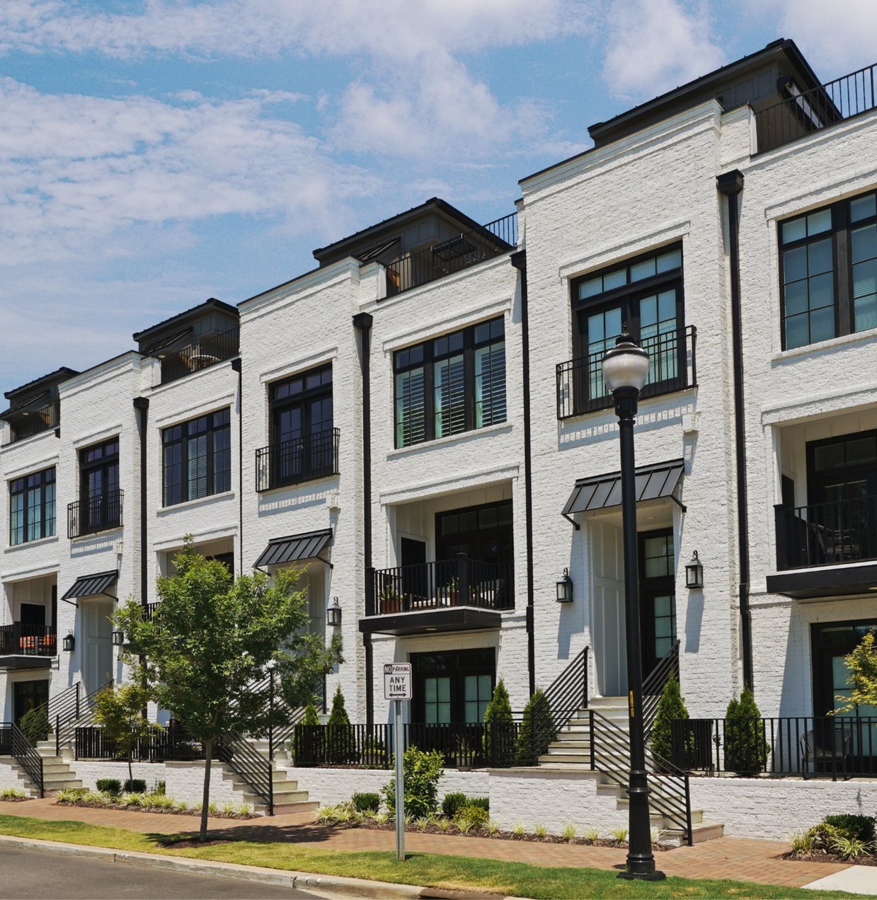 Row of newly built white-brick townhomes with black balconies